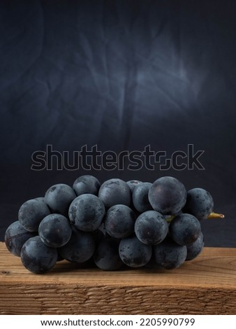 A large bunch of black grapes on a wood background