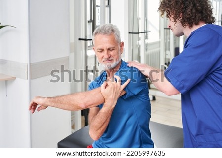 Therapist helping to old man with back in medical rehabilitation and physical therapy centre