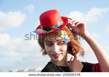 portrait of a cheerful clown with the red hat on the background of blue sky