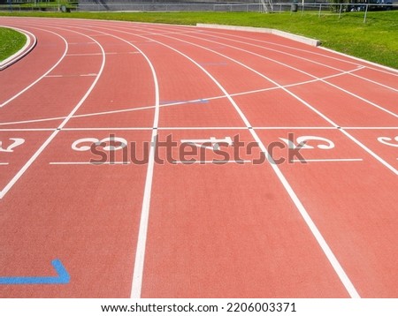 White numbered lanes on red synthetic running track