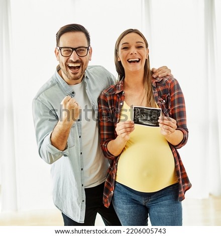 Happy young couple, pregnent woman, holding and showing ultrasound scan picture at home