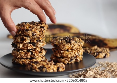 Healthy evening snacks made of rolled oats, pureed ripe plantains and raisins. Shot on white background with ripe plantain and oats around Royalty-Free Stock Photo #2206014805