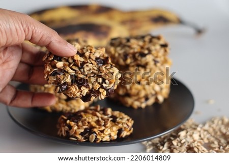 Healthy evening snacks made of rolled oats, pureed ripe plantains and raisins. Shot on white background with ripe plantain and oats around Royalty-Free Stock Photo #2206014809