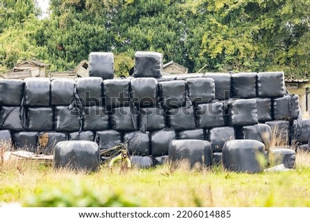 Black plastic covered hay bales, stacked ready for winter use