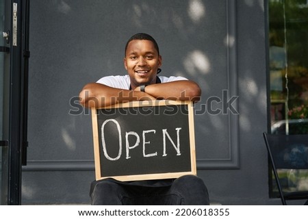 Smiling young man holding an open sign