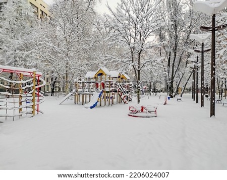 An empty and snow-covered childrens playground in the early December morning