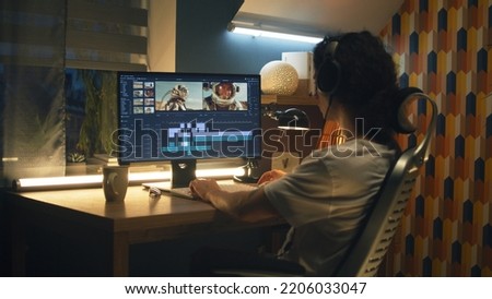 Guy in headphones editing video with astronauts for space blog in professional program while working remotely on computer at home Royalty-Free Stock Photo #2206033047