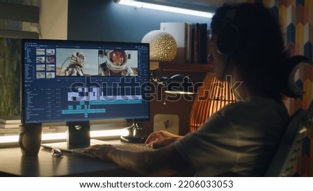 Guy in headphones editing video with astronauts for space blog in professional program while working remotely on computer at home