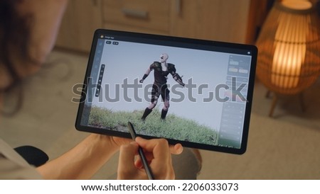 Male 3D designer creating 3D animation of video game character in design application on modern digital tablet computer using stylus Royalty-Free Stock Photo #2206033073