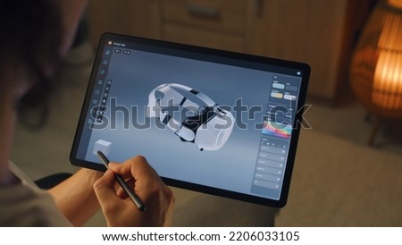 Young male 3D designer drawing and creating 3D prototype of VR headset in professional design application on tablet using digital pencil