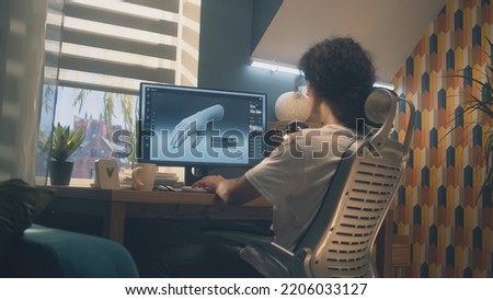Male designer sitting on chair at the table at home office and making 3D prototype of human hand in professional program for 3D, modelling using pc.