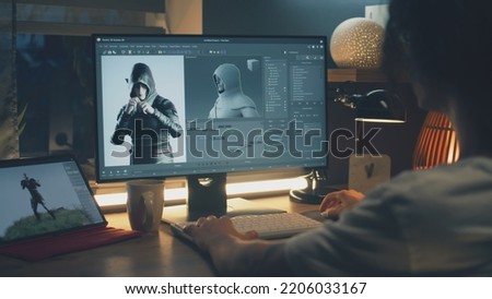 Male 3D designer sitting at the table at home and making animation for video game character, using modern computer and software for creating 3D modeling projects Royalty-Free Stock Photo #2206033167