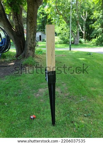 A fence spike setup in a lawn with a board in it all ready to hit down into the ground as a fence is being installed.