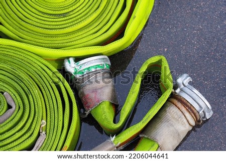 Equipment for fire fighting. Rolled into a roll, green fire hoses with aluminum connective couplings on road, top view
