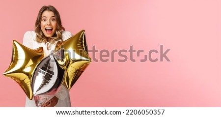 Holidays, celebration and women concept. Happy charming and surprised girl being congratulated with birthday, holding star-shaped balloons and smiling joyfully camera, pink background