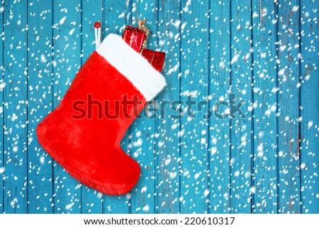 Red christmas boot with gifts on background wooden wall