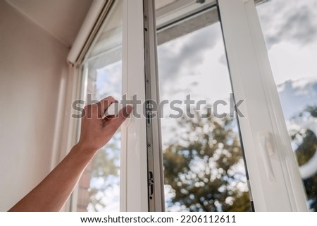 One sided open window. A hand opens a vinyl plastic window on a blue sky background. Royalty-Free Stock Photo #2206112611