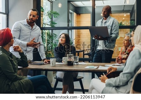 Creative business professionals having a group discussion during a meeting in a modern office. Team of multicultural businesspeople sharing ideas in an inclusive workplace. Royalty-Free Stock Photo #2206113947