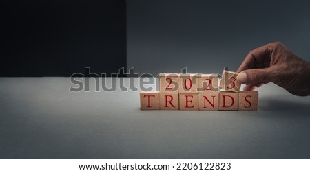 concept of trends for 2023 ,hand posing blocks on blue grey background with copy space .