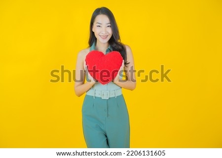 Portrait beautiful young asian woman smile with heart pillow shape on color background