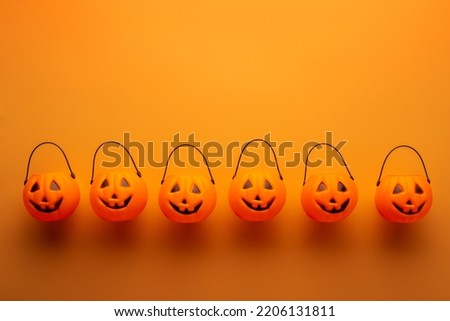 Halloween decorations with pumpkin baskets on orange background