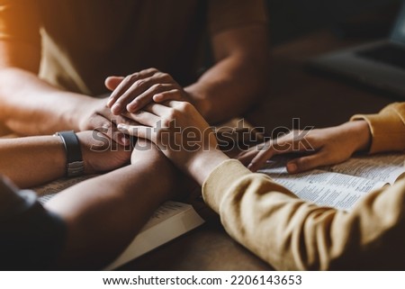 Christian group of people holding hands praying worship together to believe and Bible on a wooden table for devotional for prayer meeting concept. Royalty-Free Stock Photo #2206143653