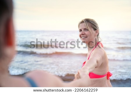 follow me swimming. Smiling girl standing at sea and invites you to swim, follow me travel concept. Young woman in follow me pose enjoying the summer.