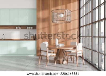 Stylish kitchen interior with dining table and chairs on grey tile floor. Cooking and eating area with panoramic window on city view. 3D rendering