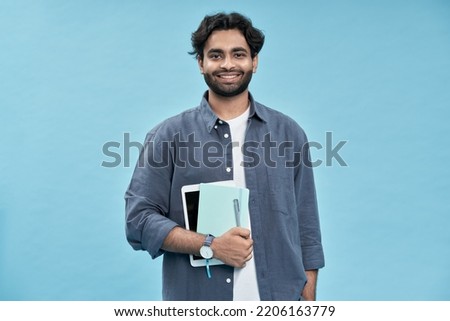 Smiling happy arab young man student standing isolated on blue background. Business education concept, remote online learning and elearning, distance studying, grant scholarship programs.