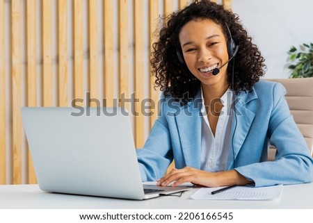 Businesswoman with elegant suit sitting at computer desk in the office and joining in a video conference - Beautiful adult woman working at laptop and telephone online for a customer care company Royalty-Free Stock Photo #2206166545