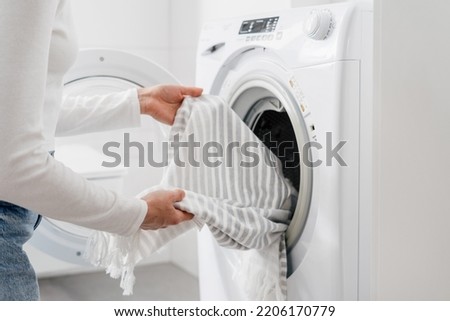 cropped shot of female hands put bed linen or cotton towel in automatic washing machine with open door in bathroom, housekeeping duties Royalty-Free Stock Photo #2206170779