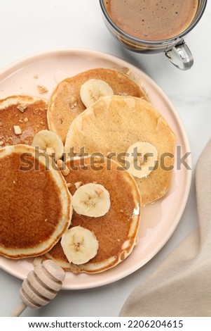 Tasty pancakes with sliced banana served on white marble table, flat lay