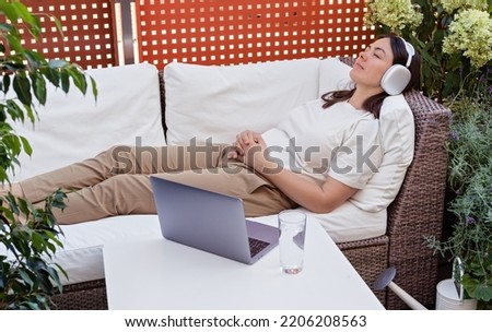 Young woman having online hypnotherapy regression or meditation session with psychotherapist lying on sofa on balcony at home. Digital service business Royalty-Free Stock Photo #2206208563