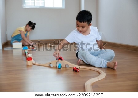 Asian cute girl playing wood block building rail way and road on the floor at home. 
