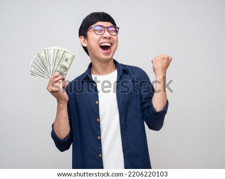 Young asian man holding money show fist up apreeciate happy about earn money Royalty-Free Stock Photo #2206220103