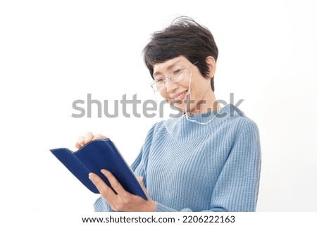 Asian middle aged woman reading a book in white background