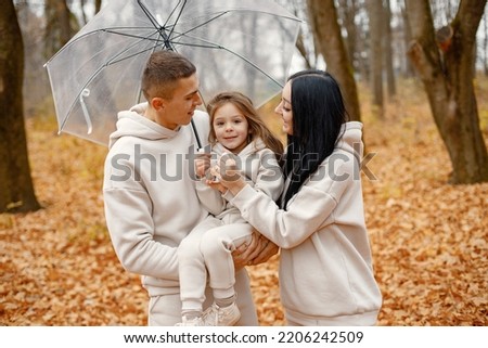 Young family standing in autumn forest under transparent umbrella Royalty-Free Stock Photo #2206242509