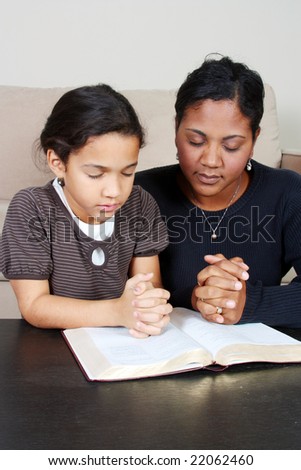 Minority woman and her daughter praying together