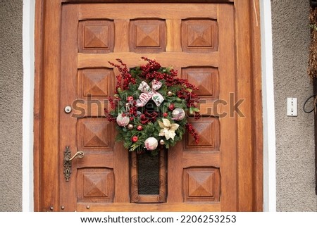 Door with evergreen festive holiday decoration, Christmas wreath with with red beads and baubles
