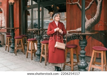 Elderly senior woman walking at cafe table in restaurant. Old retired aged lady on walk on city street. Stylish elegant elder person pensioner. Quite calm happy years in metropolis. Royalty-Free Stock Photo #2206254117