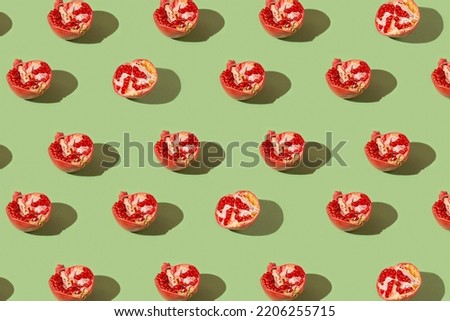 Creative pattern made of fresh pomegranates on green background with shadows. Refreshment concept. Healthy food ingredient theme.