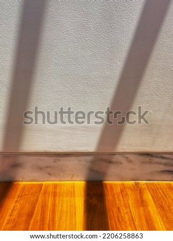 aesthetic close up shot of wooden flooring joint with white marble wall and white wall finish sun shading or sun shined with sun ray shadowing pattern for architectural background ideas