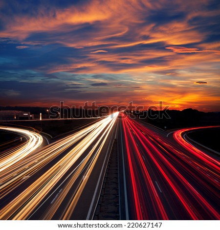 Speed Traffic at Dramatic Sundown Time - light trails on motorway highway at night,  long exposure abstract urban background Royalty-Free Stock Photo #220627147
