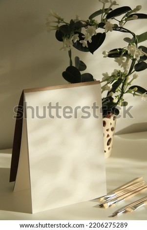 blank white paper sheet and plant in a pot with natural sunlight and shadows