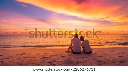 Love couple watching sunset together on beach travel summer holidays. People silhouette from behind sitting enjoying view sunset sea tropical island, destination vacation. Romantic freedom lifestyle
