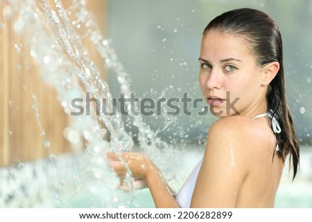 Beautiful woman bathing in spa looks at you under water jet