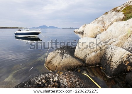 Aluminium boat tied to rocks on a still day at Norwegian coast