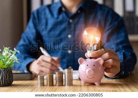 business man holding a light bulb shine an idea with stacks of coins stacked New ideas for saving money, taxes, retirement money