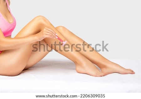 The girl shaves her legs.hair removal procedure on a woman’s body. Removing unwanted body hair.  Royalty-Free Stock Photo #2206309035