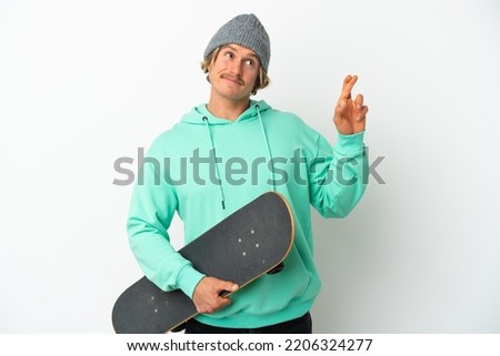 Young skater blonde man isolated on white background with fingers crossing and wishing the best